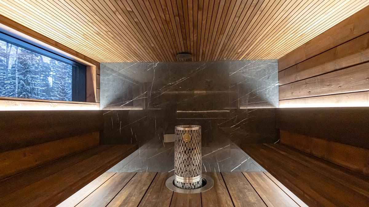 L'illuminazione indiretta su due livelli nella sauna è sufficiente per l'intero spazio. Le luci sono montate dietro lo schienale per illuminare verso l'alto e sotto la seduta per illuminare verso il basso